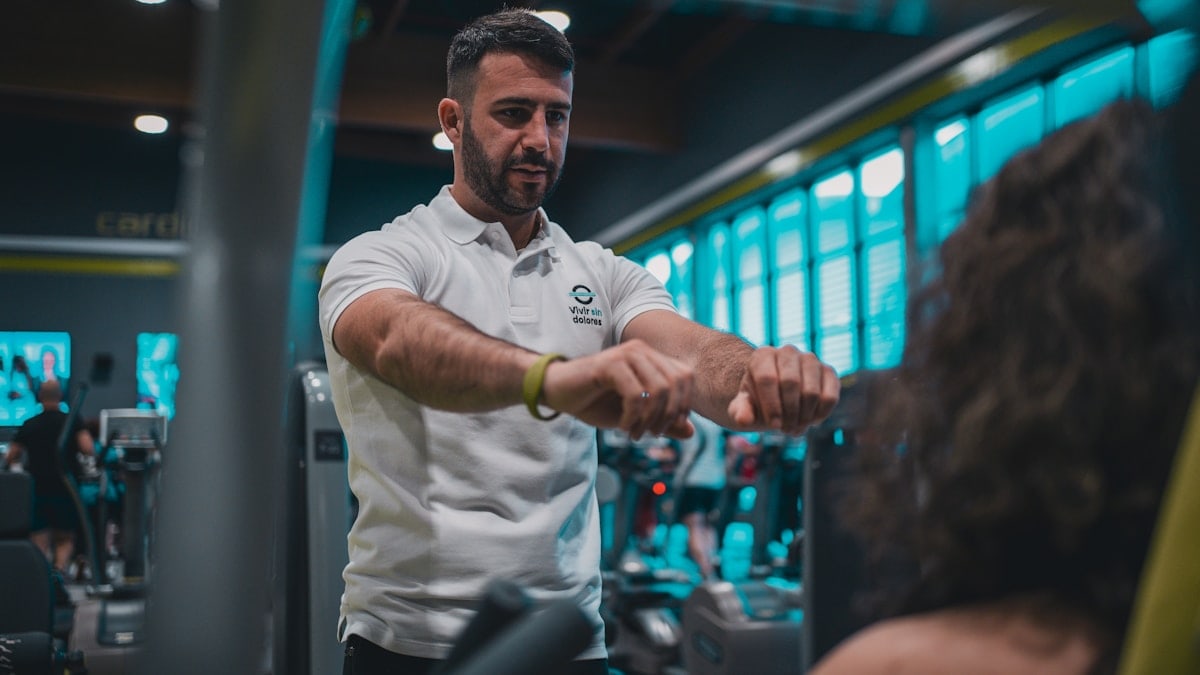 Sesión de entrenamiento en el gimnasio con un entrenador personal, enfocada en el rendimiento y el bienestar físico.